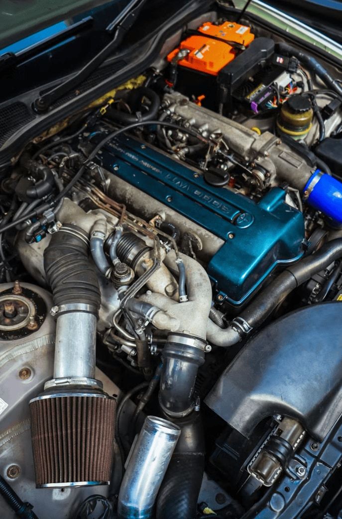 Engine bay with the hood open, showing the engine, hoses and air intake